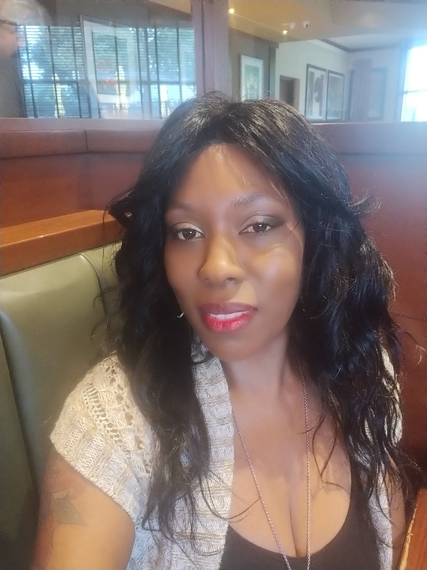 Shavanesse Grant seated in a restaurant booth, wearing a light-colored cardigan over a dark top